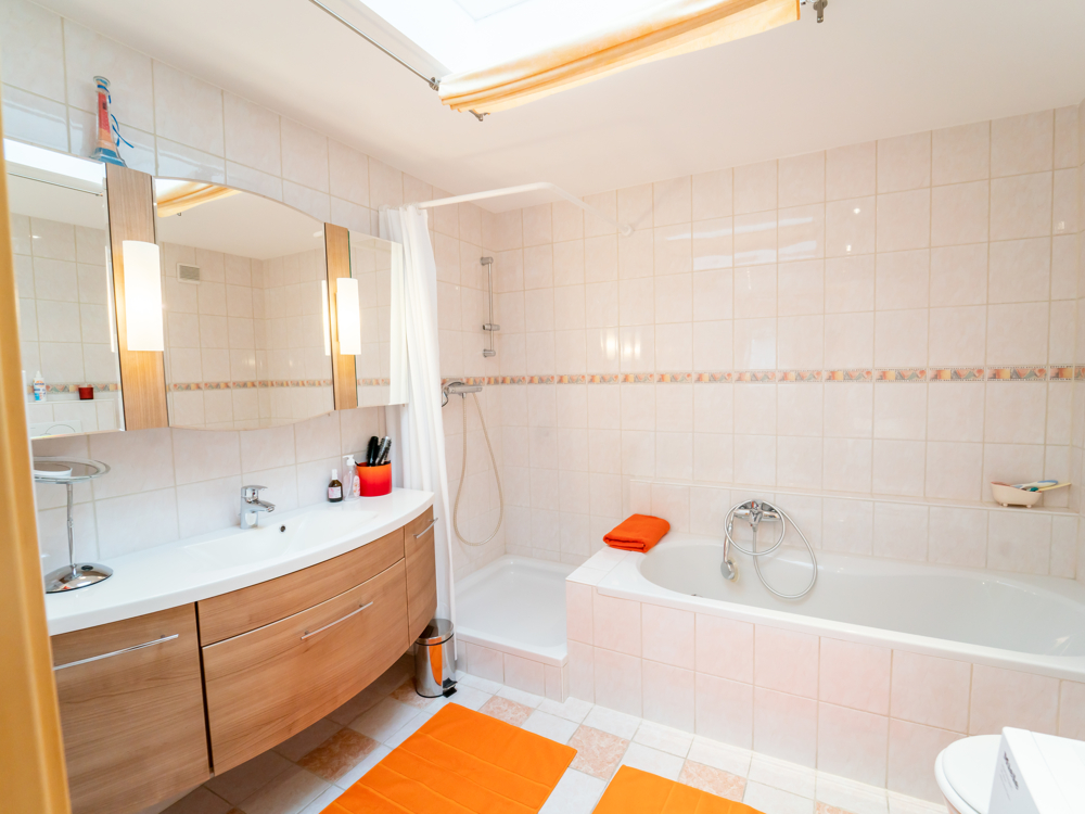 Lichtdurchflutetes Badezimmer mit Badewanne, Dusche und öffenbarem Dachfenster