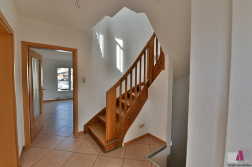 Flur mit originaler Holztreppe und Blick auf das Wohnzimmere