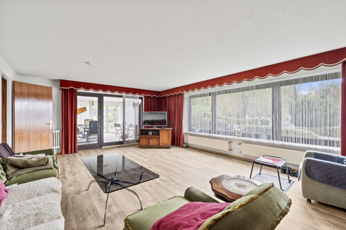 Wohnzimmer mit großer Fensterfront und Ausgang zum Wintergarten