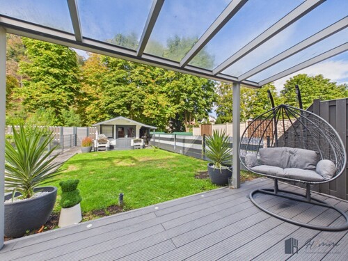 Viel Platz für die Familie: Die überdachte Lounge-Ecke und der pflegeleichte Garten mit Gartenhaus
