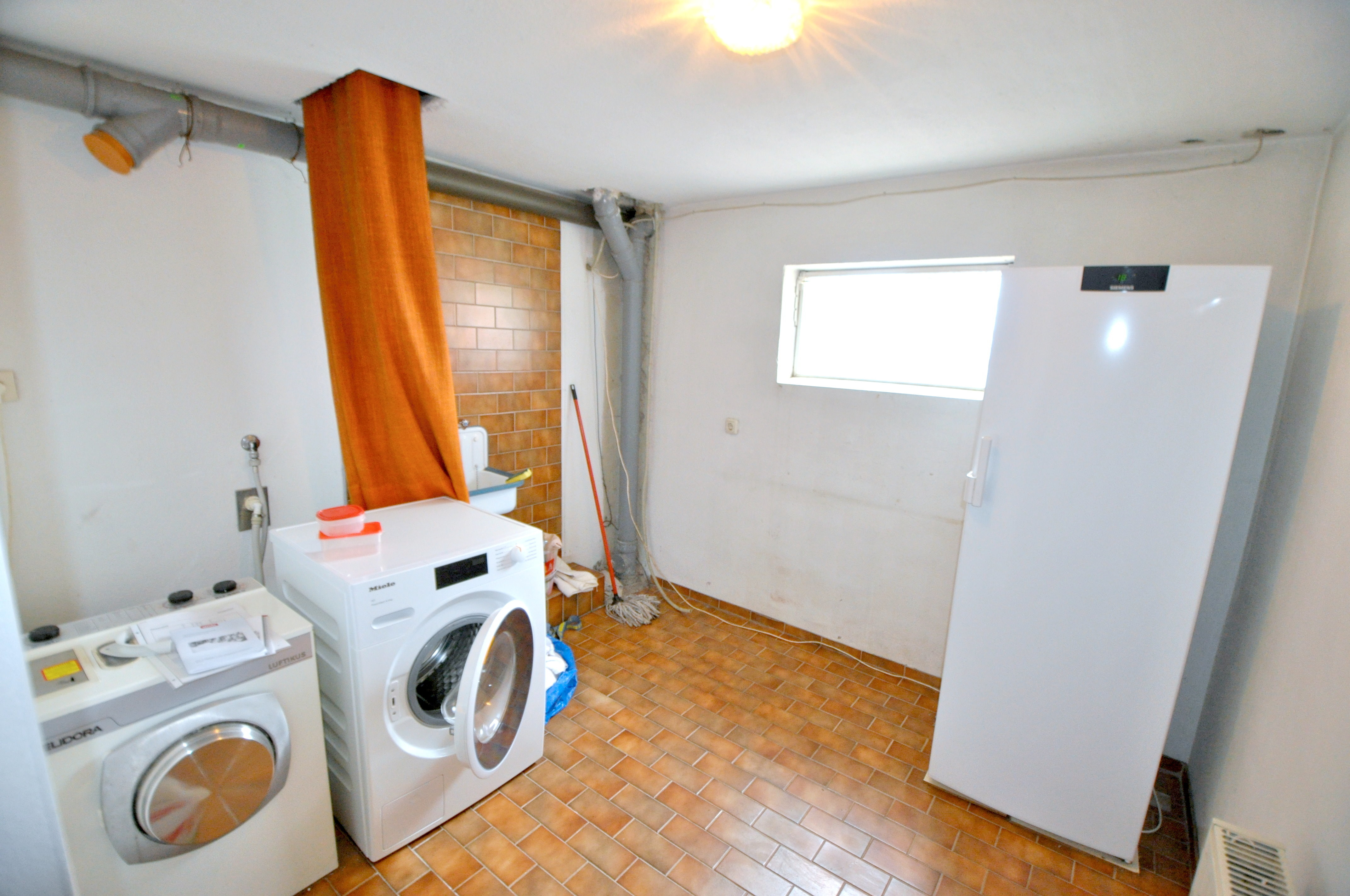 Waschmaschinenraum mit Wäscheabwurf aus dem Badezimmer im EG