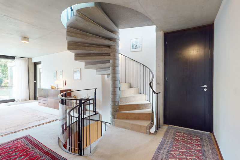 Eingangsbereich mit Sichtbeton Wendeltreppe und Blick zum Wohnzimmer