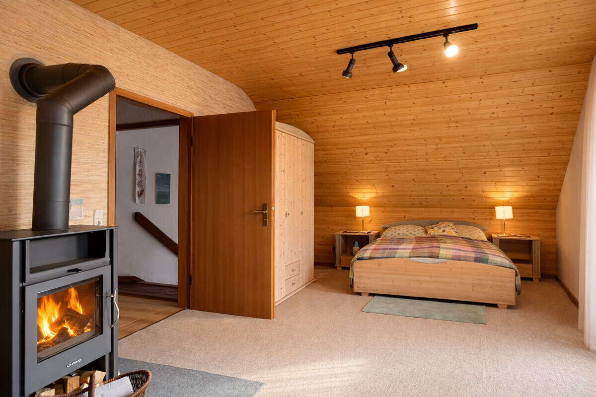 Schlafzimmer 1 OG mit Holzofen u. Balkonzugang