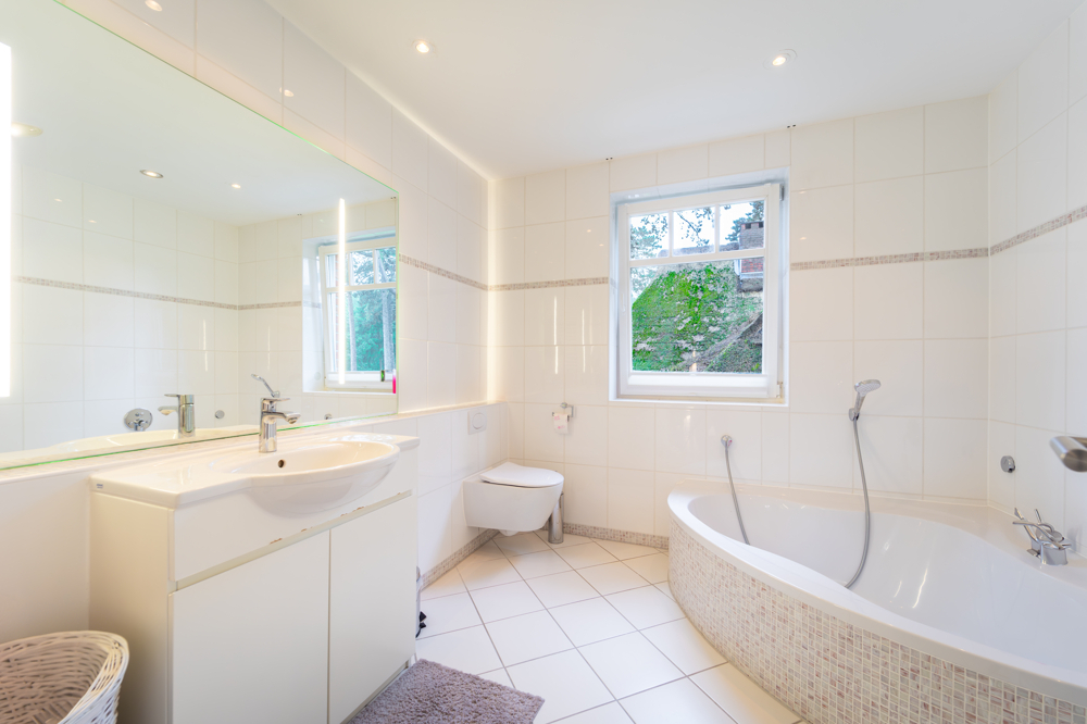 Modernes Vollbad mit Fliesenbelag im linken Flügel