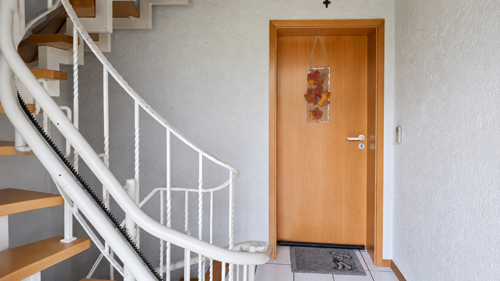 Einladender Zugang mit charmanter Holztreppe und Treppenlift