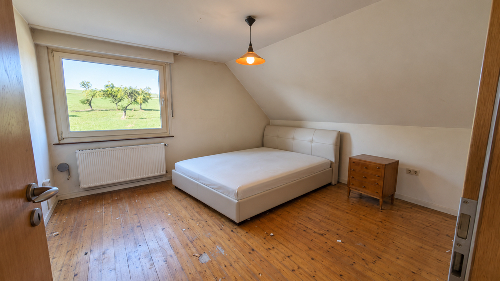 Schlafzimmer mit Holzboden und Fernsicht im Dachgeschoss