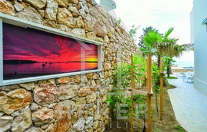 Die Steinmauer mit den mediterranen Bäumen im garten der Luxus-Villa.