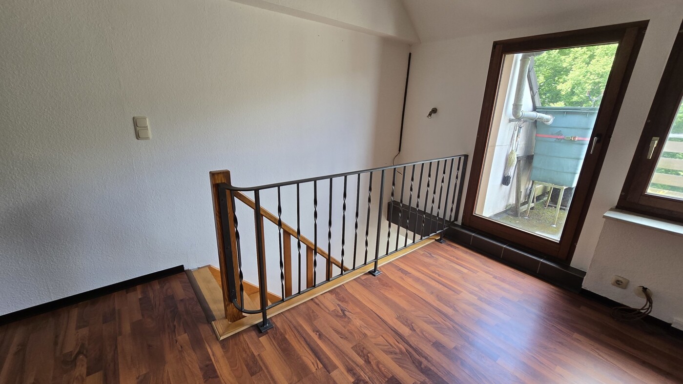 Wohnzimmer mit Treppenaufgang und Zugang Dachterrassse
