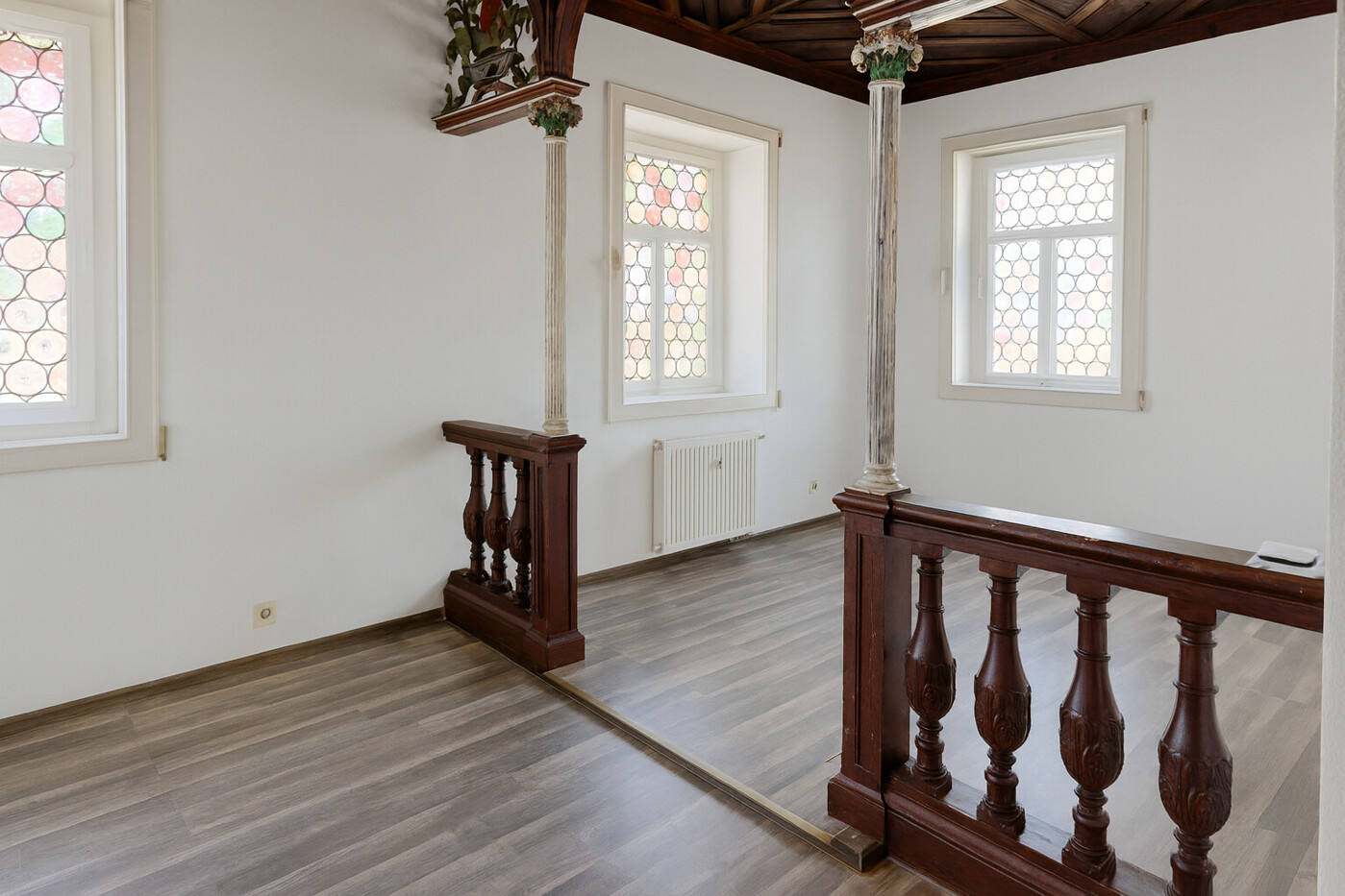Stilvolle Galerie im Wohnzimmer mit antiken Säulen und kunstvoll gearbeiteter Holzbalustrade