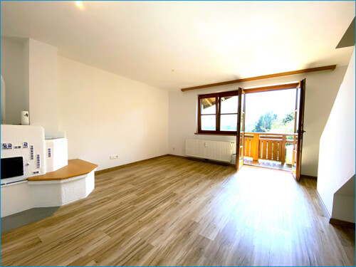 großzügiges Wohnzimmer mit Holzofen und Zugang zum Südbalkon